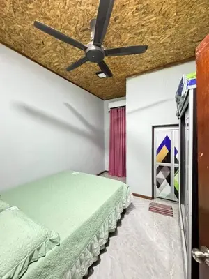 a bedroom with a ceiling fan and a green bed at Damai Homestay in Gua Sai