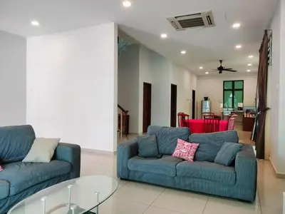 a living room with two blue couches and a glass table at Woon homestay 2 in Balik Pulau
