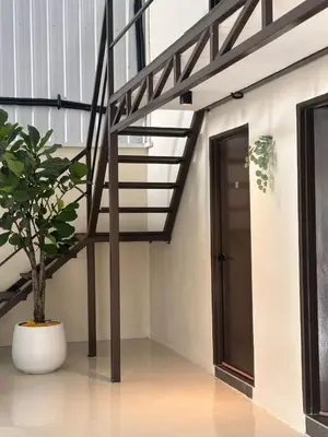 a hallway with a staircase and a door and a plant at Lumen Stay in Bukit Mertajam