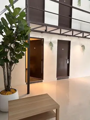 a wooden bench in a room with a potted tree at Lumen Stay in Bukit Mertajam