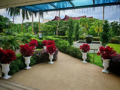 a garden with white vases filled with red flowers at Sri Sayang Homestay 2 in Batu Ferringhi