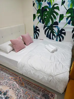 a bed with white sheets and pink pillows on it at Qalsharyna Chalet inn in Simpang