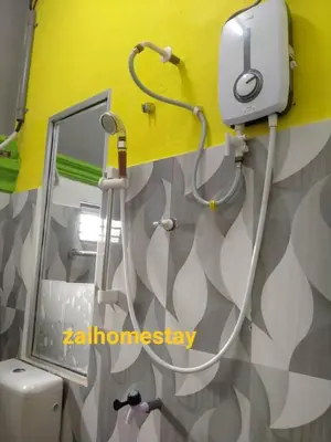 a bathroom with a mirror and a hair drier on the wall at Zai homestay in Kampung Jeram Kawang