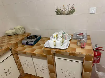 a kitchen with a table with cups and dishes on it at 786 Bali Top Homestay in Sungai Petani