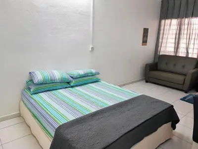 a bed with two pillows and a chair in a room at Cozy Home near Airport, & Bayan Lepas Industrial in Bayan Lepas