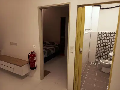 a bathroom with a toilet and a bedroom with a bed at IFS Soho 3 Basic Home in Seri Iskandar