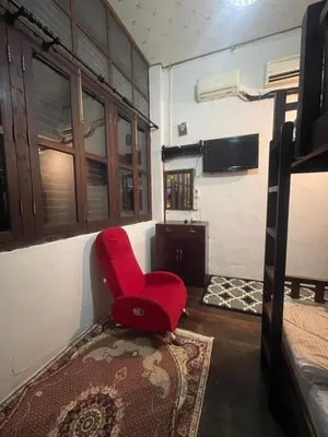 a red chair sitting in the corner of a room at Pearl Heritage Guesthouse in George Town