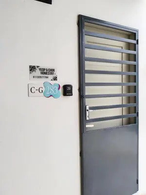 a metal door with a sign on a wall at Yeop & Chor Homestay in Seri Iskandar
