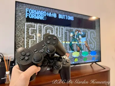 a person holding two video game controllers in front of a tv at BBC De Garden Homestay in Ipoh