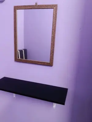 a mirror on a wall with a black shelf at Homestay Sayang in Ipoh