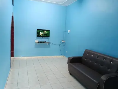 a living room with a black couch and a blue wall at Homestay Sayang in Ipoh