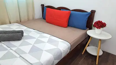 a bed with colorful pillows and a table with a vase at MediSehat KamarKu - Just 20 meters to Gleneagles Hospital Penang in George Town