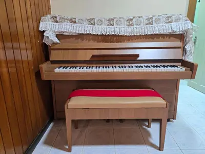 a wooden piano with a stool in a room at House of Lights in Batu Gajah