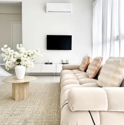 a white living room with a couch and a tv at The Urban Suites City&seaview in Jelutong