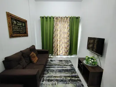 a living room with a couch and a green curtain at Seri Homestay Apartment Seri Iskandar in Seri Iskandar