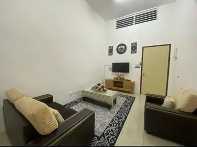 a living room with two couches and a television at Chinta Homestay in Kampong Ayer Melintas Besar
