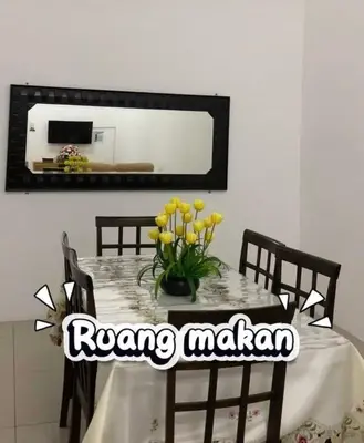 a table with a vase of yellow flowers on it at Chinta Homestay in Kampong Ayer Melintas Besar