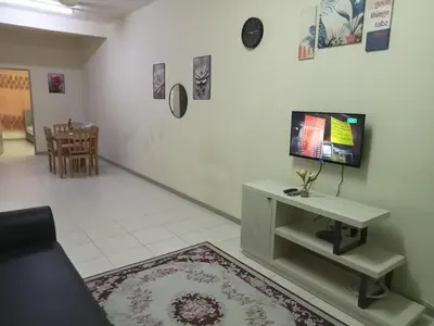 a living room with a table and a tv on a wall at Hani Homestayz2U in Kuala Lipis