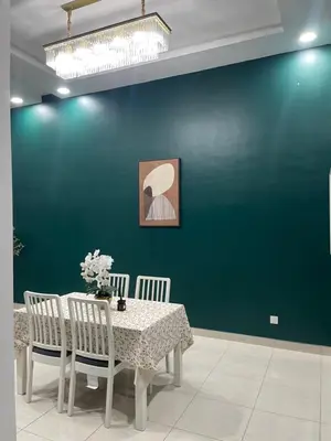 a dining room with a table and a green wall at Nafisa Homestay in Kepala Batas