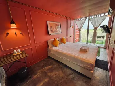 a bedroom with a bed with red walls and a window at PadiBox Homestay in Sekincan