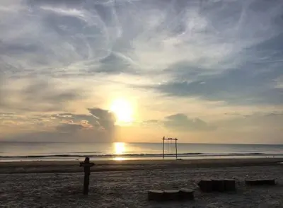 a person standing on a beach with the sun setting at Homestay Selesa KPP Guest House in Gua Sai