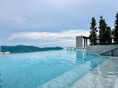 a large swimming pool with blue water and trees at Romantic Sea & Penang Bridge View Luxury 2BR in Bayan Lepas