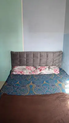 a bed with a brown headboard in a room at Homestay Kak Su Seri Iskandar in Seri Iskandar