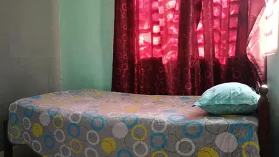 a bed with a pillow and a window with curtains at Homestay Kak Su Seri Iskandar in Seri Iskandar