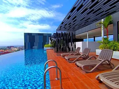 a row of chaise lounge chairs next to a swimming pool at Horizon Rooftop Skypool Condotel - Ipoh in Ipoh