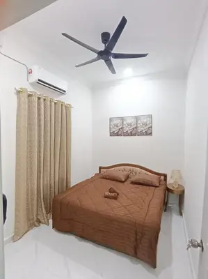 a bedroom with a bed with a ceiling fan at Airisafiq Homestay in Kampong Sungai Rambai