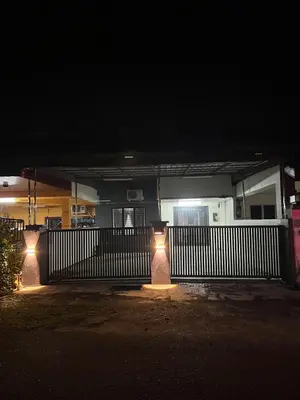 a house with lights in front of a fence at night at Classic Pearl Homestay in Teluk Intan