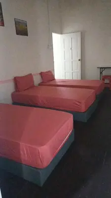 two beds in a room with red sheets at POLI Homes in George Town