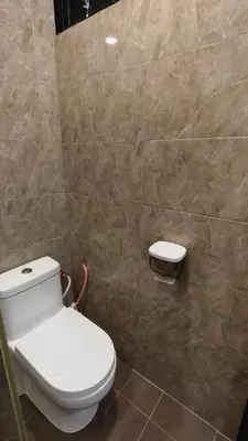 a bathroom with a toilet and a tiled wall at DouDou's House in Simpang Ampat