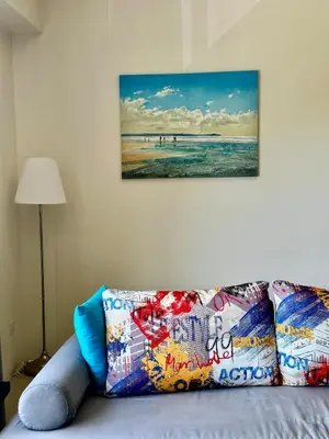 a couch in a room with a picture of the beach at By The Sea partial seaview 2BR 6pax Batu Ferringhi in Batu Ferringhi