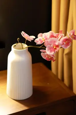 a white vase with pink flowers on a table at The Cintra Muse Hotel at Central of Georgetown and UNESCO in George Town