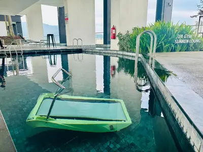 a swimming pool with a green boat in the water at Urban Suites 3R2B 11pax Deluxe Living Room in George Town
