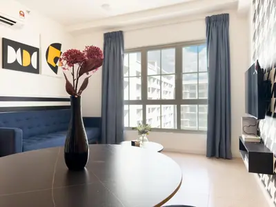 a vase with flowers on a table in a living room at Stallionz Ipoh by ANGO in Ipoh