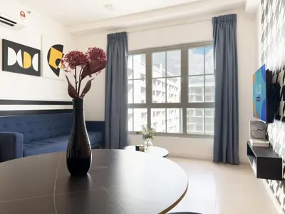 a living room with a table and a vase with flowers at Stallionz Ipoh by ANGO in Ipoh