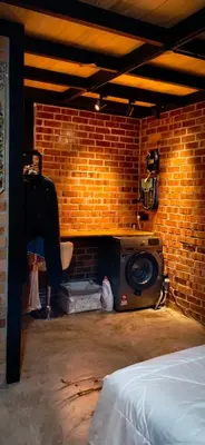 a room with a brick wall with a speaker and a bed at Sekinchan Tiny House in Sekincan