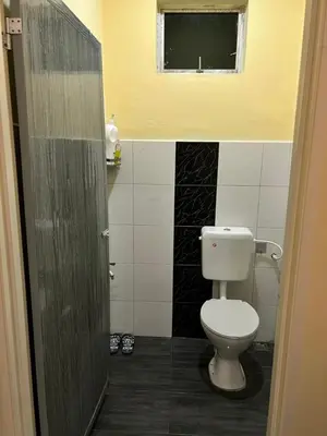a bathroom with a white toilet and a window at Homestay D'Kampong in Teluk Intan