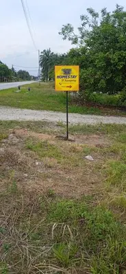 a yellow sign sitting on the side of a road at Homestay D'Kampong in Teluk Intan