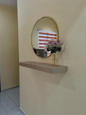 a mirror on a wall with a vase of flowers on a shelf at Homestay D'Kampong in Teluk Intan