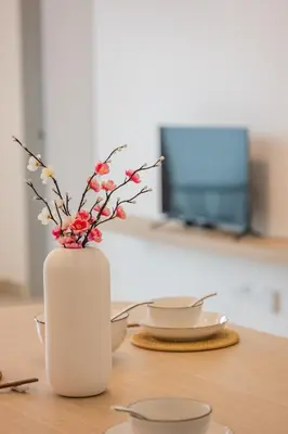 a white vase with flowers in it on a table at Serene Muji Family Retreat 2-7 pax with Comfortable Living Space in Tanah Rata