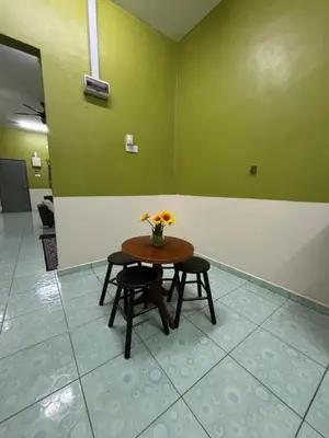 a table with two chairs and a vase of flowers at Wawa Homestay Ipoh in Ipoh
