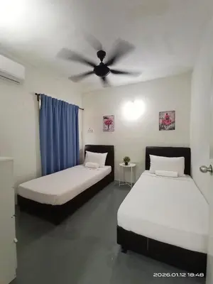 two beds in a room with a ceiling fan at Adno Homestay Batu Kawan 5SB in Simpang Ampat