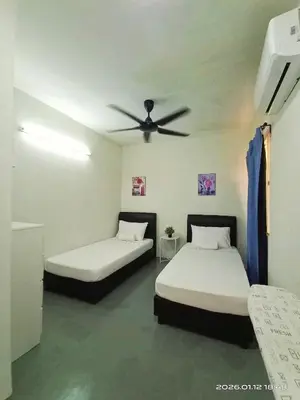 two beds in a room with a ceiling fan at Adno Homestay Batu Kawan 5SB in Simpang Ampat
