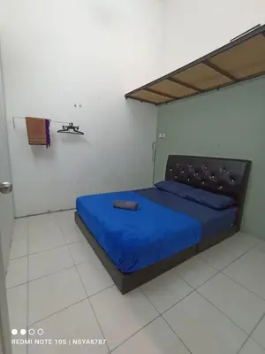 a bedroom with a bed with a blue bedspread at De Ariffa Homestay مسلم in Lahat