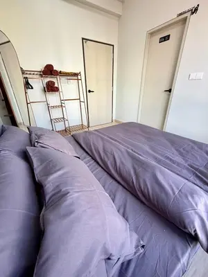 a bed with purple pillows in a room with two doors at Piccadilly Ipoh by Iconique in Ipoh