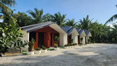 a row of cottages on the beach with palm trees at Swit60 Homestay in Sungai Besar