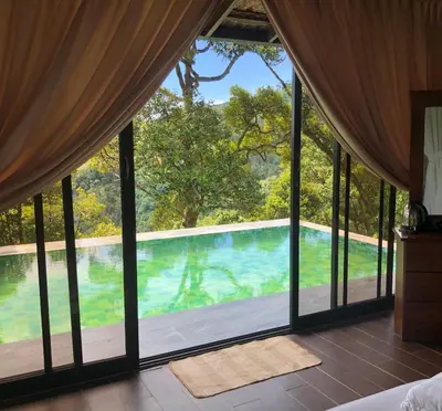 a bedroom with a view of a swimming pool through windows at Bao Sheng Durian Farm in Balik Pulau
